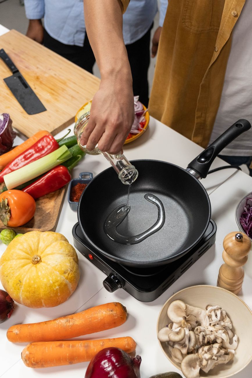 person pouring cooking oil in frying pan