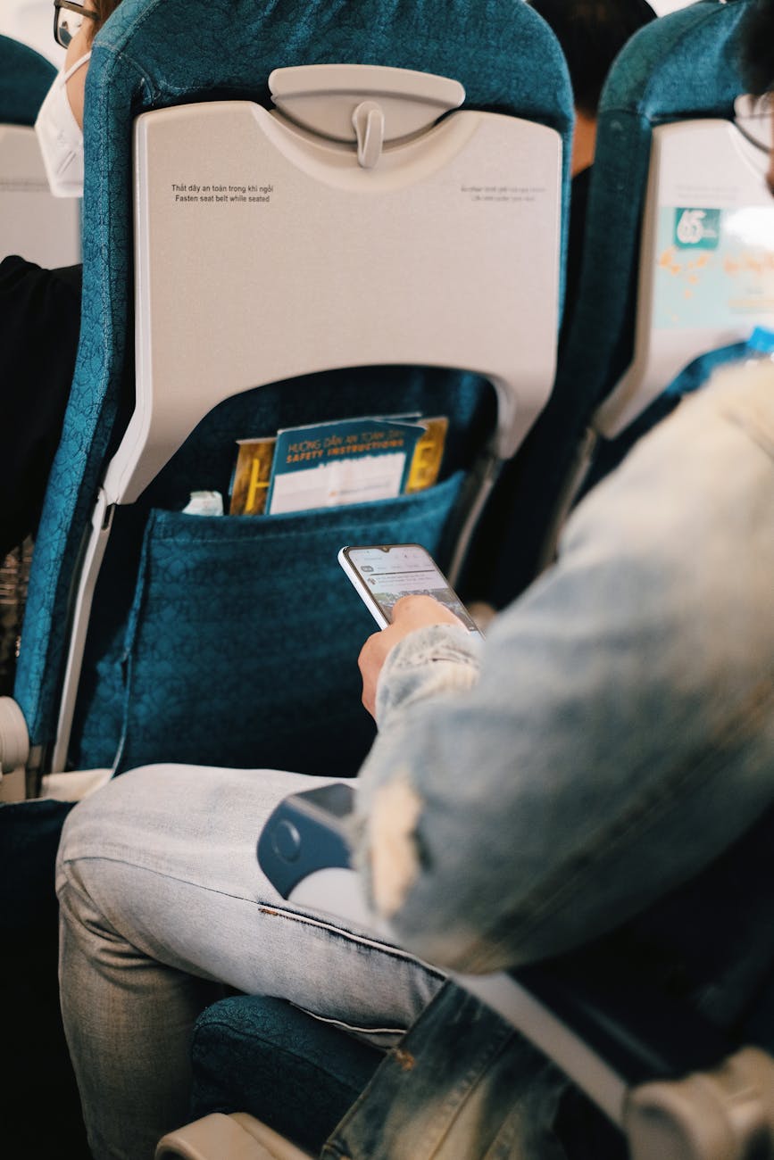 person using his smartphone while sitting inside the plane