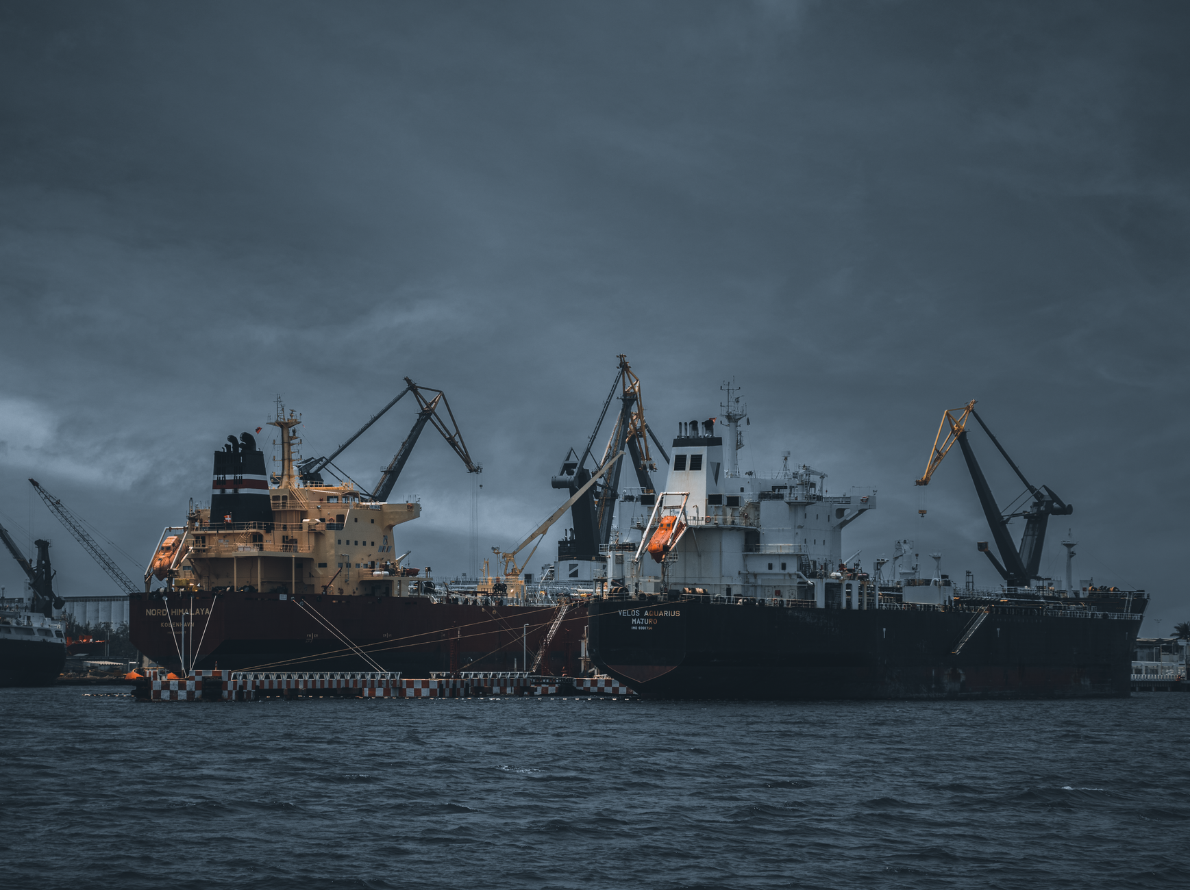 industrial cargo ships docked at port with cranes